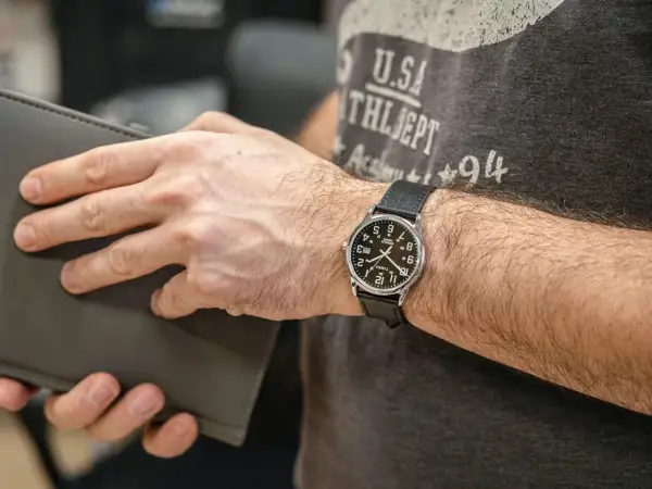 Mężczyzna z zegarkiem Timex, który jest znany z trwałości i przystępności. Klasyczny design, idealny na co dzień.