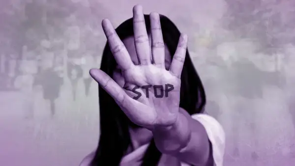 Mano extendida con la palabra "STOP" escrita, simbolizando cómo ayudar a una mujer maltratada.