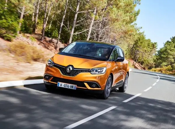 Pomarańczowy Renault Scenic 4 na krętej drodze. Choć wygląda świetnie, warto znać jego potencjalne wady przed zakupem.