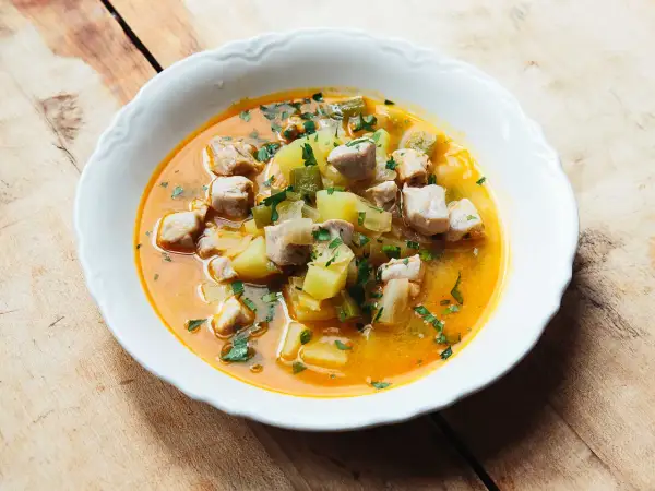 A hearty bowl of marmitako recipe, featuring tender tuna chunks, potatoes, and peppers in a rich, savory broth, garnished with fresh parsley.