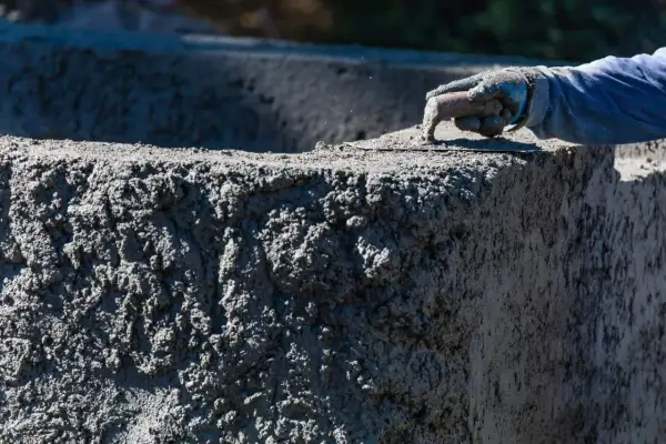 Ręka w rękawicy wygładza świeży beton B20. Sprawdzamy beton B20 cena za m3.