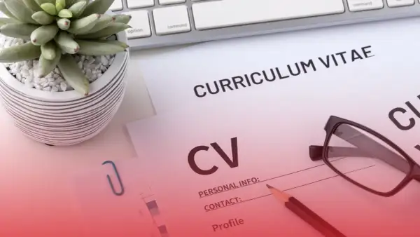 Na biurku leżą dokumenty CV, okulary i ołówek. Roślina w doniczce i klawiatura dopełniają scenę.