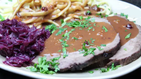 Sauerbraten rezept: Zarte Scheiben Braten mit dunkler Soße, dazu Rotkohl und Spätzle. Ein Klassiker der deutschen Küche.