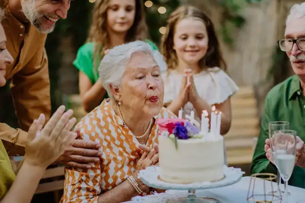 Babcia zdmuchuje świeczki na torcie, rodzina składa życzenia na 51 urodziny.