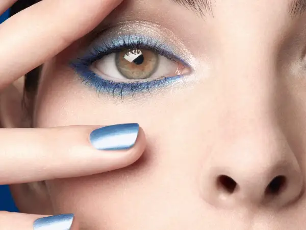 Occhi con ombretto blu elettrico e unghie abbinate, un tocco di **chanel cipria** per un look audace.