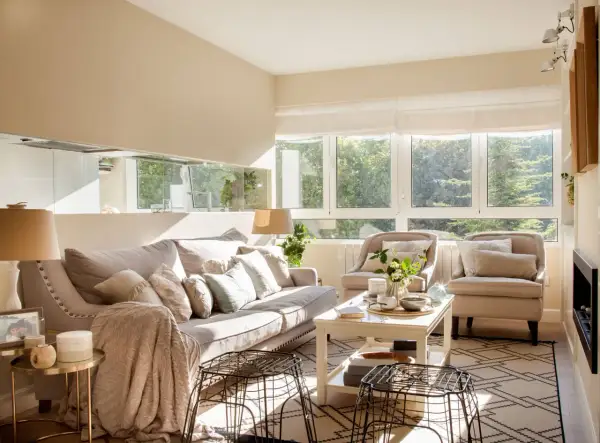 Salón luminoso con sofá y sillones en tonos neutros. La paleta de colores para pintar salones es cálida y acogedora, inspirada en la luz natural.