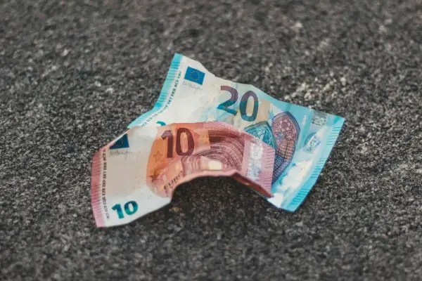 Uszkodzone banknoty 10 i 20 euro leżą na szarej powierzchni. Dowiedz się, gdzie wymienić uszkodzony banknot euro.