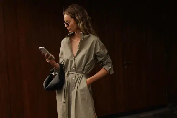 Kvinna i en snygg skjortklänning med bälte, solglasögon och handväska. En perfekt look för vårmode 2026 dam.