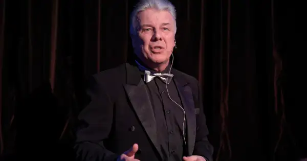 Emilian Kamiński w czarnym smokingu z muszką, jakby opowiadał o swoich filmach.
