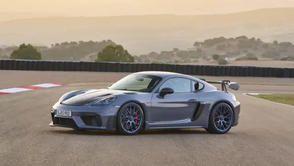 Szary Porsche GT4 RS na torze wyścigowym, z charakterystycznym skrzydłem i niebieskimi felgami.