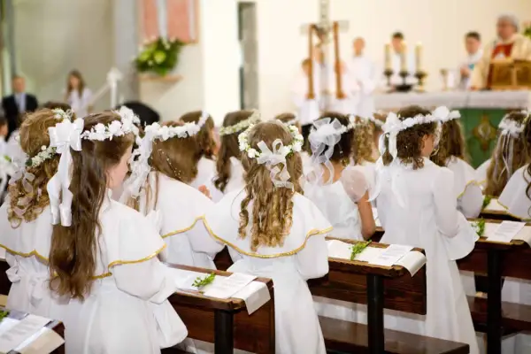 Dzieci w białych strojach, z wiankami na głowach, siedzą w ławkach kościoła. To uroczysty biały tydzień, czas pierwszej komunii świętej.