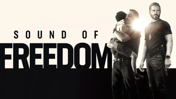 Sound of Freedom" Stream: Ein Mann umarmt ein Kind, während ein Polizist daneben steht.