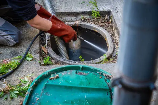 Un professionnel utilise un jet d'eau puissant pour le nettoyage du tuyau d'évacuation, délogeant les obstructions.