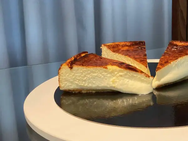 Trois parts de cheesecake basque, avec leur croûte caramélisée et leur cœur crémeux, prêtes à être dégustées.