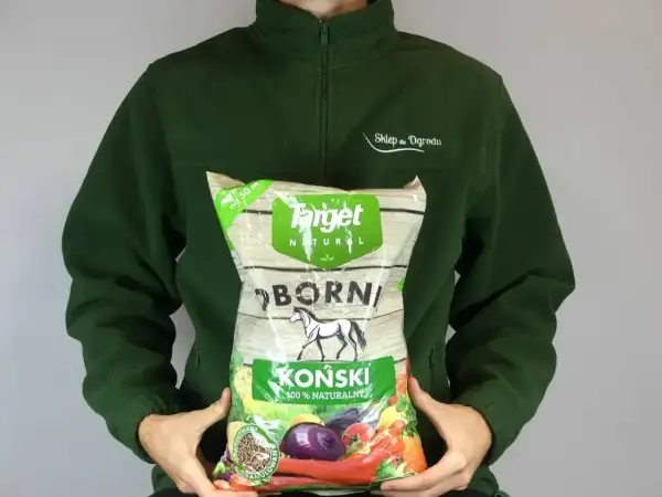 Osoba trzyma worek z napisem "Obornik Koński 100% Naturalny". Granulowany nawóz dla roślin.