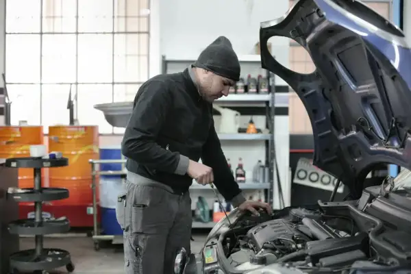 Mechanik sprawdza silnik, zastanawiając się, ile kosztuje roboczogodzina w warsztacie samochodowym.