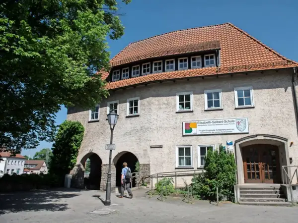Elisabeth-Selbert-Schule, eine der besten Schulen Deutschlands, mit ihrem markanten roten Ziegeldach und einem Schild, das auf ihre Rolle als regionales Kompetenzzentrum hinweist.