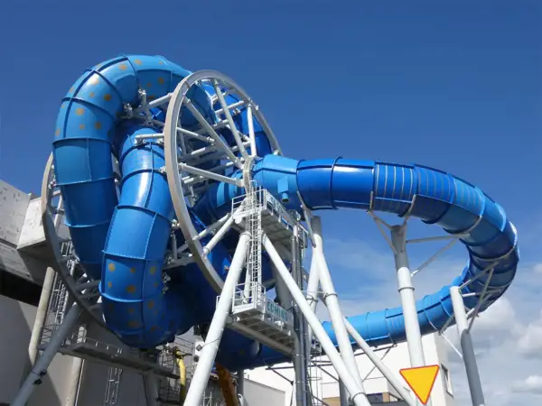 Aquapark Reda: niebieska zjeżdżalnia z rekinami, wirująca konstrukcja z rur, podniebna przygoda.