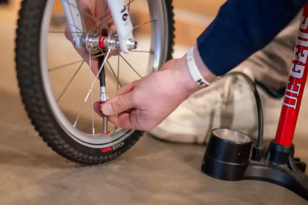 Hand sluit fietspomp aan op ventiel. Zo pomp je een fietsband op voor een soepele rit.