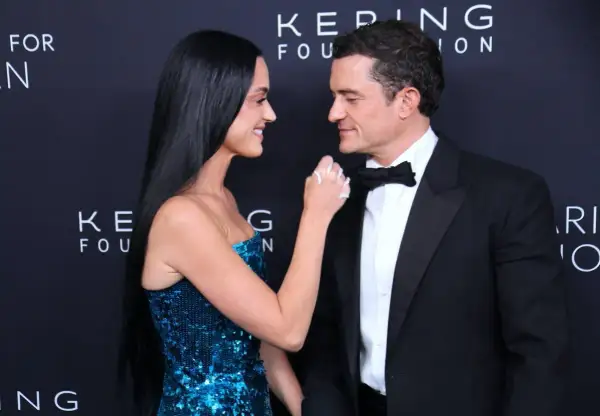 Katy Perry i Orlando Bloom patrzą na siebie z czułością. Ona w błyszczącej sukni, on w eleganckim smokingu.