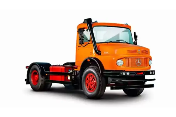 Un gros camion américain orange vif, prêt pour l'aventure, avec un échappement sur le côté.