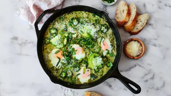 Grön shakshuka med ägg, avokado och jalapeño i gjutjärnspanna. Perfekt för ett smakrikt shakshuka recept.