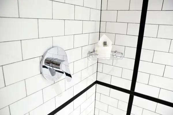 Coin de douche moderne avec robinetterie chromée et porte-savon. Idéal pour nettoyer la faience salle de bain.