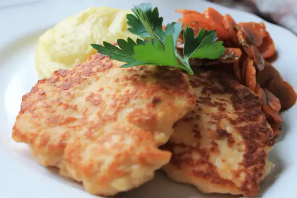 Två gyllene havets wallenbergare serveras med krämigt potatismos och glaserade morötter, toppat med en kvist persilja.