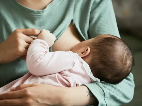 Mama karmi dziecko. Piersi są pełne mleka, co może powodować uczucie twardości przy karmieniu.