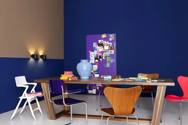 Zweifarbig gestrichene Wand in Blau und Beige mit einem Holztisch, bunten Stühlen und einer Pinnwand. Tolle wand zweifarbig streichen ideen!