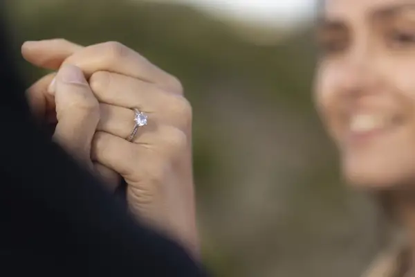 Delikatne pierścionki z diamentem, idealne jako pierścionki zaręczynowe. Biżuteria z diamentami na dłoni z jasnoróżowym manicurem.