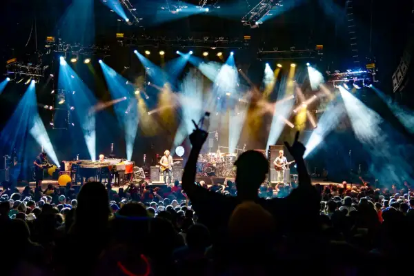 Capturing the energy of a live show is key to how to become a concert photographer. This image shows a band performing under dramatic stage lights to an enthusiastic crowd.