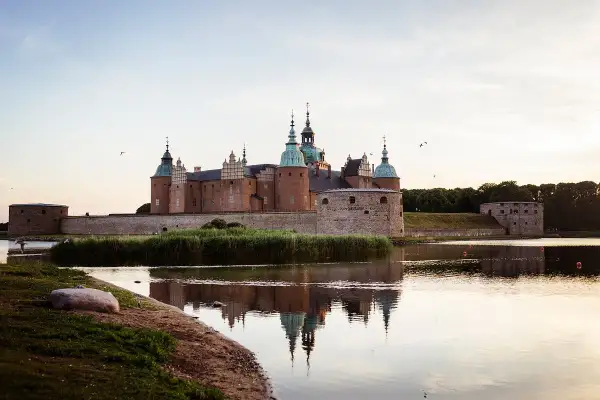Ett ståtligt slott i Småland speglar sig i vattnet.