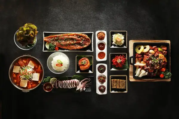 Zestaw koreańskich potraw: zupa, ryba, kalmar, kimchi, ryż i dodatki.