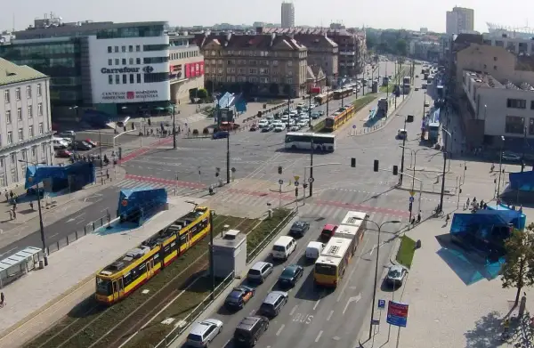 Żółty tramwaj na skrzyżowaniu z samochodami i autobusem.