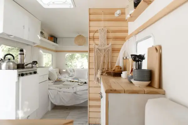 L'habitacle du camion aménagé offre une cuisine fonctionnelle et un coin couchage douillet, décoré d'une macramé murale.
