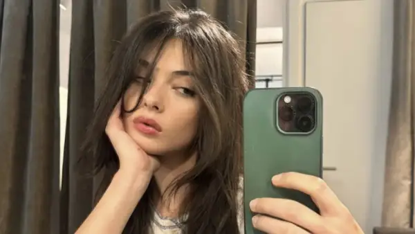 Deva Cassel se toma un selfie con su teléfono, apoyando la barbilla en la mano.