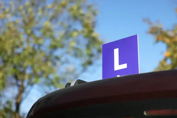 Niebieska tabliczka z literą "L" na dachu samochodu, symbolizująca naukę jazdy. Czy to zapowiedź najtrudniejszych pytań na prawo jazdy kat B?