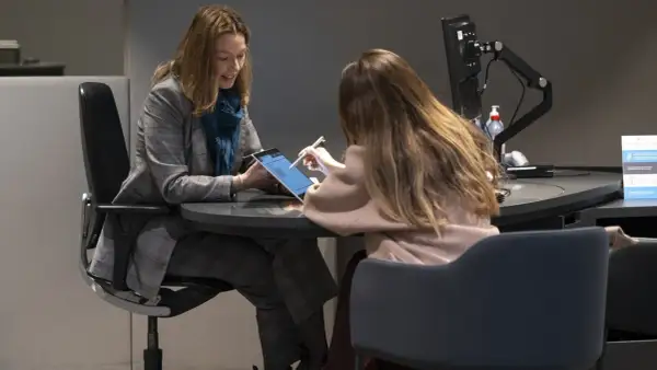 Dos mujeres revisan una tablet, discutiendo una posible hipoteca de 100.000 euros a 15 años.