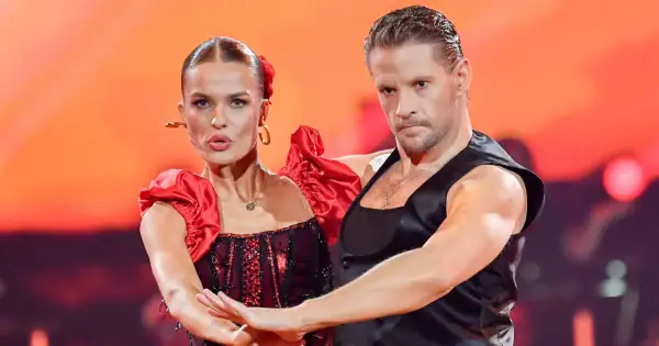 Para tańczy w strojach inspirowanych folklorem. Kobieta w czerwonej sukni z falbankami, mężczyzna w czarnej kamizelce.