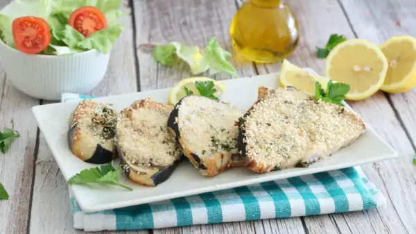 Fette di pesce spada in friggitrice ad aria, impanate con semi di sesamo e erbe aromatiche, servite con limone e insalata.