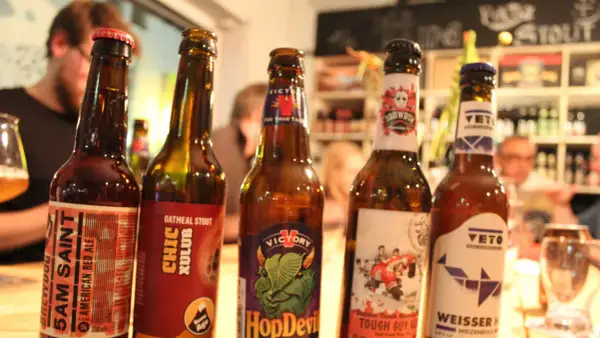 Fünf Flaschen Craft Beer stehen nebeneinander. Jede Flasche hat ein einzigartiges Etikett, das die Vielfalt von Craft Beer zeigt.