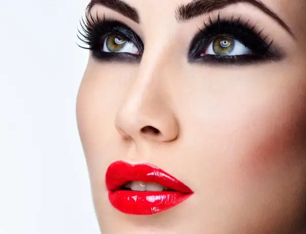 Occhi con smokey eyes e labbra sensuali con trucco con rossetto rosso brillante.