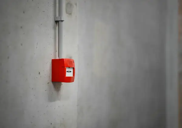 Découvrez comment fonctionne une alarme incendie : un boîtier rouge sur un mur en béton, prêt à alerter en cas de danger.
