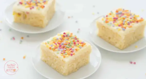 Drei Stücke saftiger konfetti kuchen mit weißer Glasur und bunten Streuseln auf weißen Tellern.