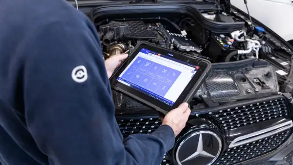 Tecnico esegue la revisione auto con tablet diagnostico, controllando i sistemi del motore.