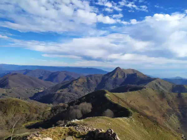 Panoramica mozzafiato del monte Matanna, con cime ondulate, boschi spogli e un cielo azzurro punteggiato di nuvole bianche.