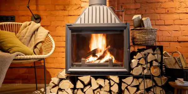 Le feu crépite dans la cheminée, mais la fumée refoule. Un fauteuil confortable et des bûches attendent.