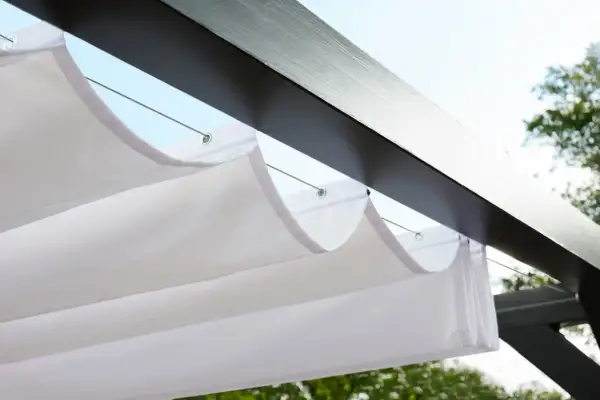 Vit markisduk hänger i vågor under en mörk pergola, perfekt för en solig dag.