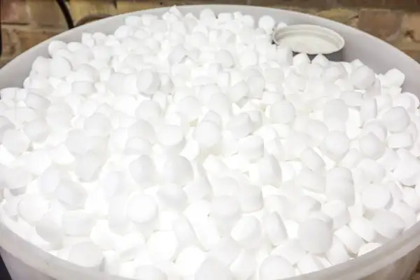 Un grand seau rempli de pastilles blanches de sel régénérant, prêtes à purifier l'eau.